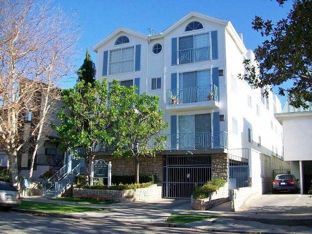 A white and blue apartment building with a black gate in front.